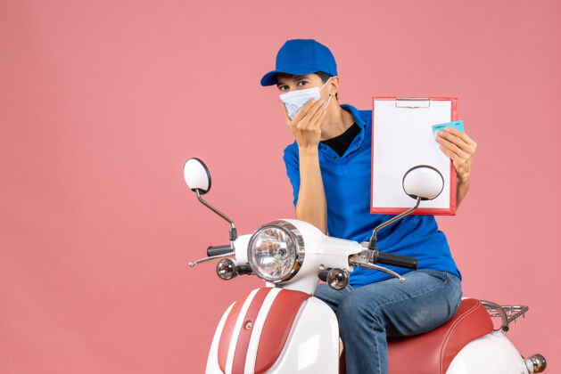 技术戴着帽子 戴着面具 坐在滑板车上 脸上挂着粉色桃色的文件和银行卡的男性送货员的俯视图文件滑板车视图