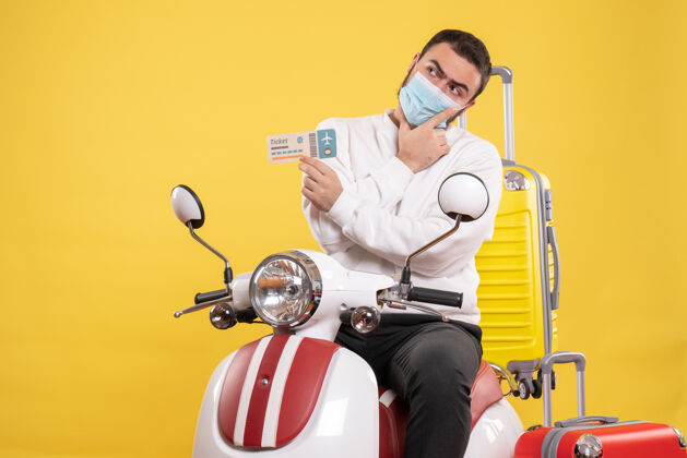 球员旅行概念的俯视图 戴着医用面罩的思考者坐在摩托车上 黄色手提箱在上面 手里拿着车票人面具旅行