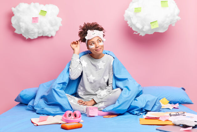 笔记本女孩穿睡衣卷发想着做创意项目躺在床上敷眼罩享受家庭氛围学生睡衣成人