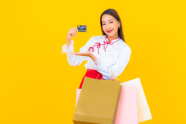 肖像一位年轻漂亮的亚洲女士 手拿购物袋 信用卡 黄色促销女性交易