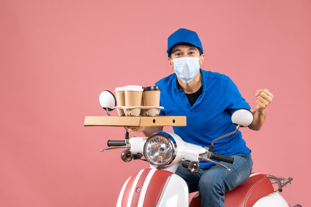 成人上图是戴着面具 戴着帽子 坐在滑板车上 在桃色背景下传递订单的疯狂情感男性送货员面具送医学
