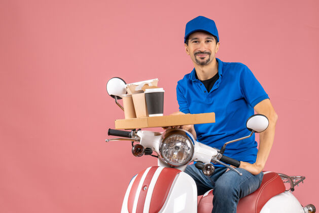 男顶视图幸福满意的信使男子戴着帽子坐在粉彩桃色背景踏板车滑板车背景人物