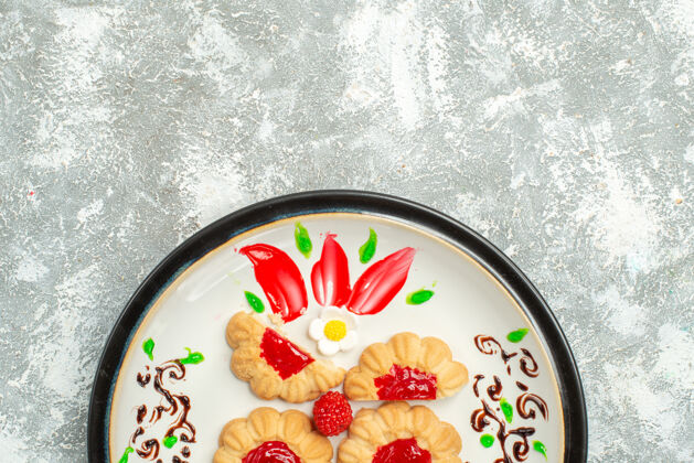 果冻顶视图美味饼干与红色果冻内板上的白色背景糖饼干蛋糕饼干甜茶盘子里面糖