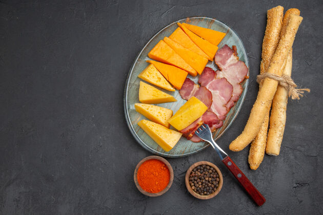 奶酪蓝色盘子上美味的香肠和奶酪片的俯视图黑色背景左侧的辣椒健康新鲜壁板