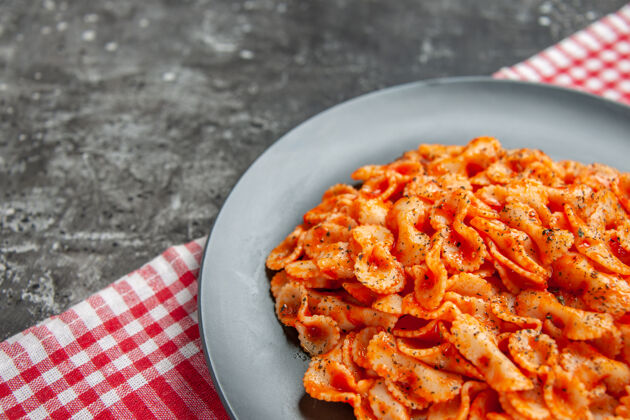 背景半张美味的意大利面 放在一个黑色盘子里 用一条红色的毛巾做晚餐晚餐美味正餐