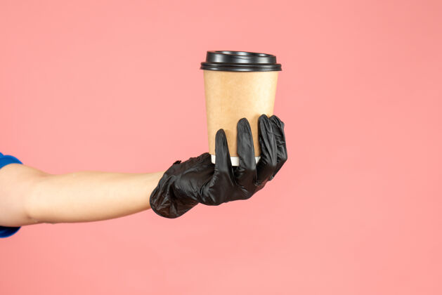 插头戴着黑手套 手拿着一杯美味的咖啡 背景是柔和的桃色粉彩帽子黑色