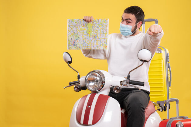 地图旅行的概念与自豪的家伙在医疗面具坐在摩托车上 黄色手提箱上 并显示黄色地图人人摩托车