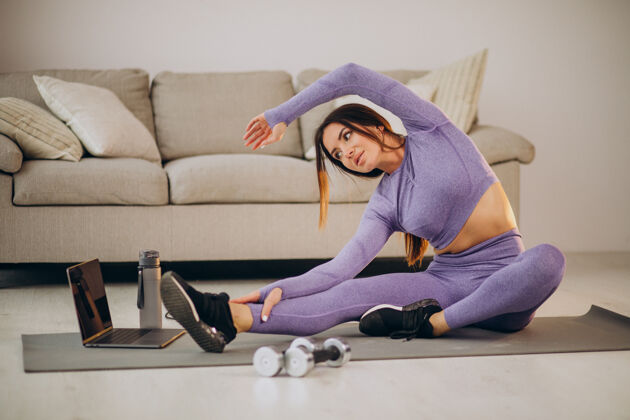 人女人在家里用跳绳和哑铃在垫子上看教程和训练形状女性体重