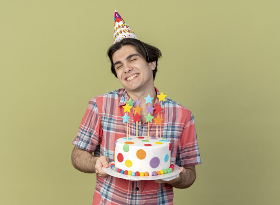 复制高加索帅哥戴着生日帽 手里拿着生日蛋糕绿色帅气蛋糕