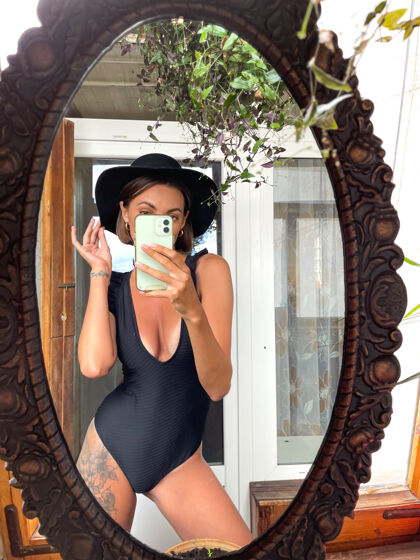 购物家里的美女穿着黑色夏季泳装 在手机上对着镜子自拍 在社交媒体上发布故事和帖子浪漫积极自画像