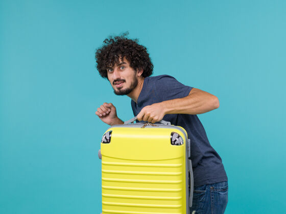 人穿着蓝色t恤的度假男人悄悄地带着蓝色的手提箱离开了假期手提箱视图