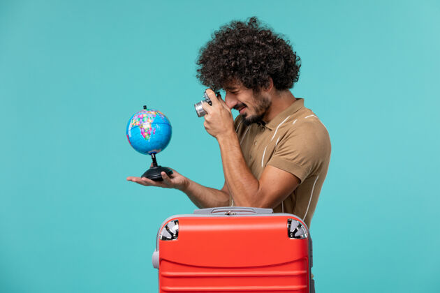 航行前视图：度假的男人拿着蓝色的小地球仪和相机蓝色旅行举行