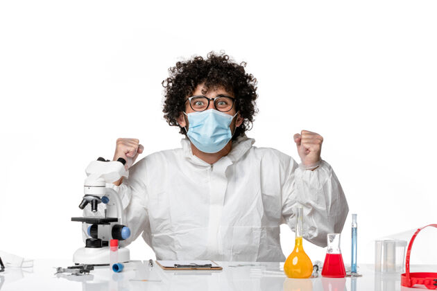 大流行男医生穿着防护服 戴着口罩坐在那里 拿着溶液在白色上欢呼雀跃面罩病毒实验室外套