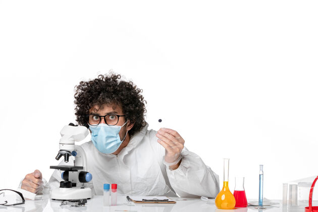 医疗男医生穿着防护服 带着无菌口罩拿着样品 用显微镜对着白色病毒防护显微镜