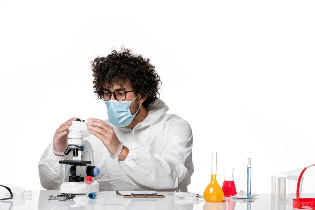 显微镜男医生穿着防护服 戴着口罩 用显微镜在白色上工作大流行男医生视图
