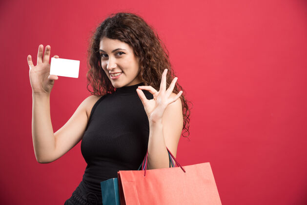 购物快乐的女人带着许多包和银行卡上的红色购买衣服包
