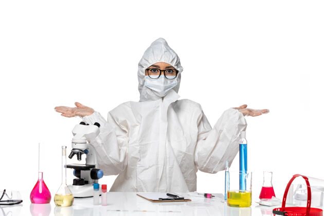 医生正面图：穿着特殊防护服的年轻女化学家坐在白色背景病毒实验室covid健康化学的溶液中实验室坐姿套装