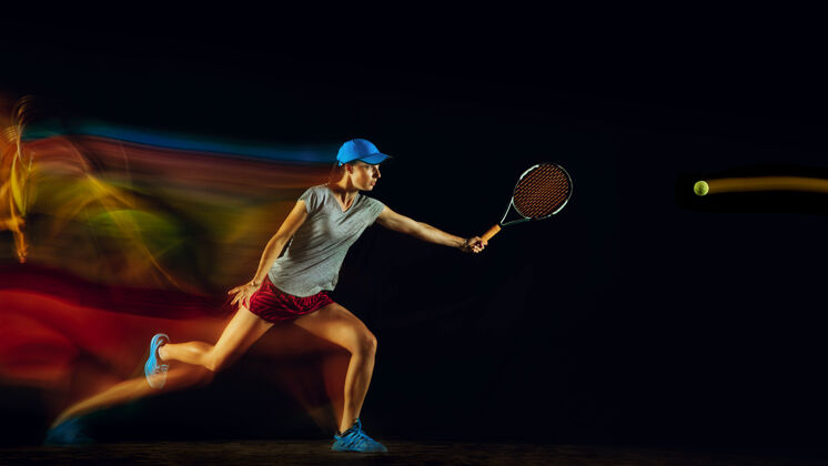混合一个打网球的女人孤零零地站在黑色的墙壁上 混合着柔和的光线女性休闲游戏