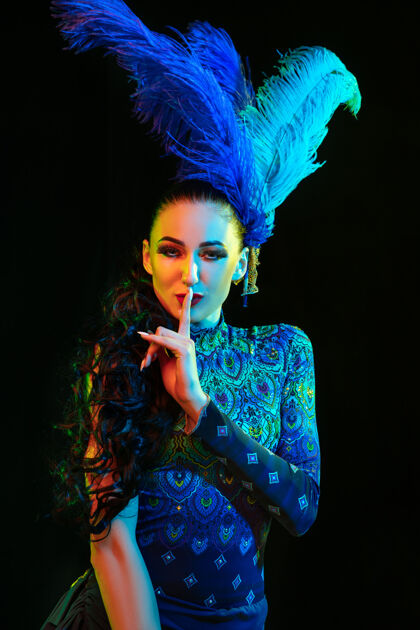巴西嘉年华里美丽的年轻女子 霓虹灯下黑色墙壁上羽毛的时尚化装服装河流威尼斯美丽