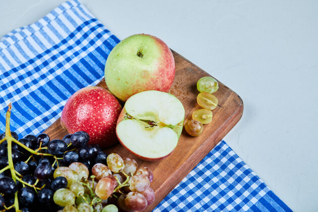餐桌用桌布把苹果和一串葡萄放在木板上深色束葡萄