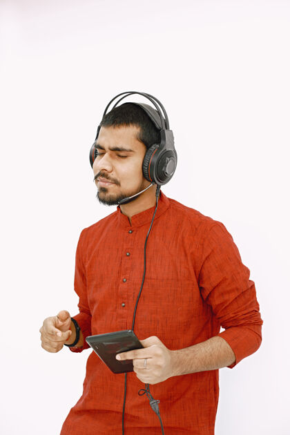 平板电脑印度年轻人戴着耳机听音乐在白墙上跳舞 与世隔绝年轻音乐年轻