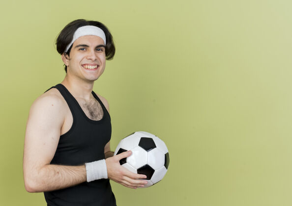 足球穿着运动服 头戴足球带 面带微笑 站着开心的年轻人运动运动装抱着