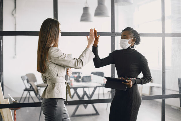 室内戴着口罩的女商人和报纸一起工作成功的公司 团队合作高五女性个人