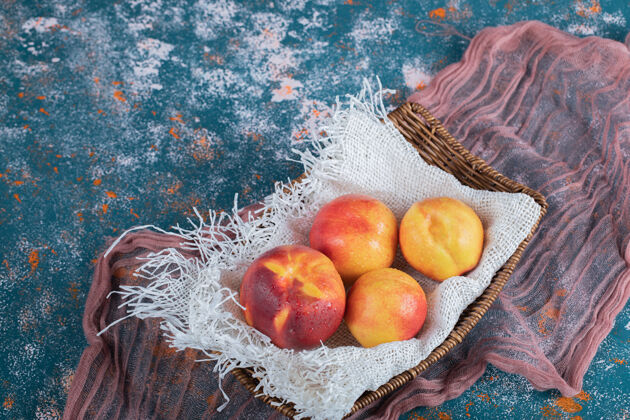 新鲜黄红色的桃子放在白色粗麻布的木篮上蔬菜异国情调产品