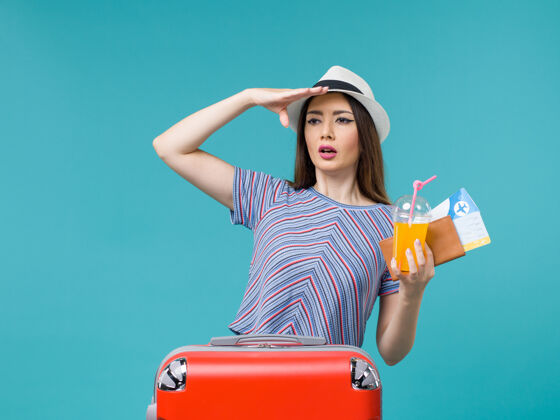 票前视图度假妇女与她的红色袋子举行门票和浅蓝色背景的果汁旅行旅行度假女性旅行女旅行果汁