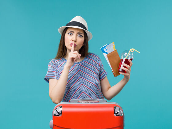 票前景度假中的女人拿着果汁拿着蓝色背景上的机票旅行女海飞机夏天成人微笑果汁