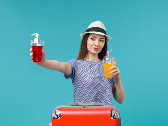 新鲜前景度假女子手持新鲜饮料上蓝色背景海上飞机航行避暑之旅成人微笑美丽