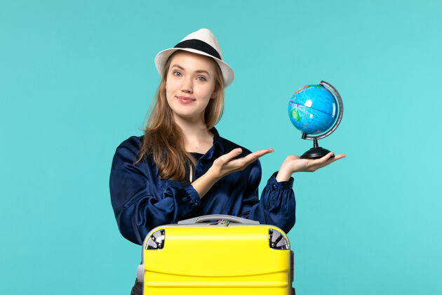 地球仪正面图年轻女子手持地球仪 准备在蓝色桌面飞机上度假女性度假之旅远航大海女性人女士