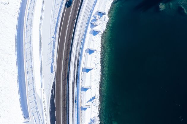 山冬季拍摄的湖旁沥青路的俯视镜头路天空树