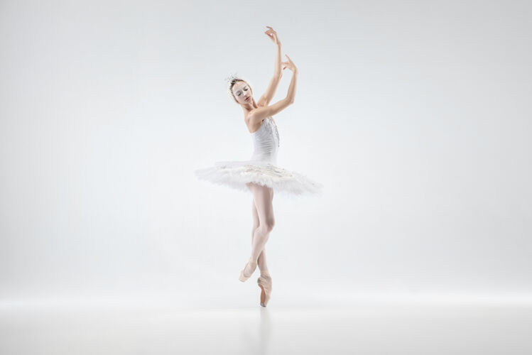 年轻以白色工作室为背景的年轻优雅的芭蕾舞演员艺术家喜悦移动
