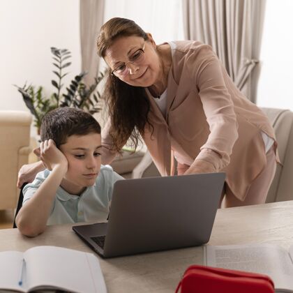 世代小男孩和奶奶在笔记本电脑上做作业室内女人家庭作业
