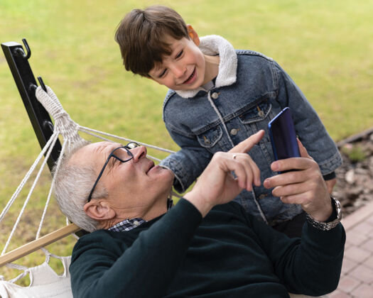 横向爷爷在外面和他的孙子拿着电话外部老人男人