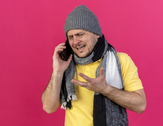 电话悲伤的男人警告冬天的帽子和围巾在电话上说粉红色年轻男人恼怒
