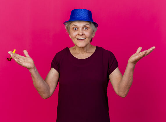 哨子惊讶的戴着派对帽的老太太吹着粉红色的口哨聚会老人帽子