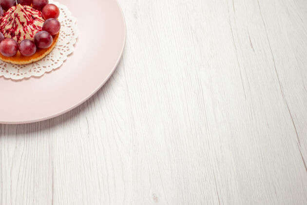餐正面图：白色桌上的水果甜点蛋糕 盘子里有葡萄前面水果食物