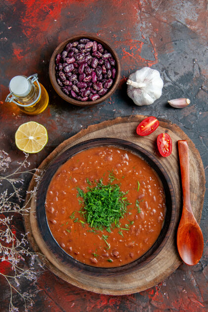 豆番茄汤在棕色碗里的垂直视图油瓶豆子和调羹在混色桌上餐油汤