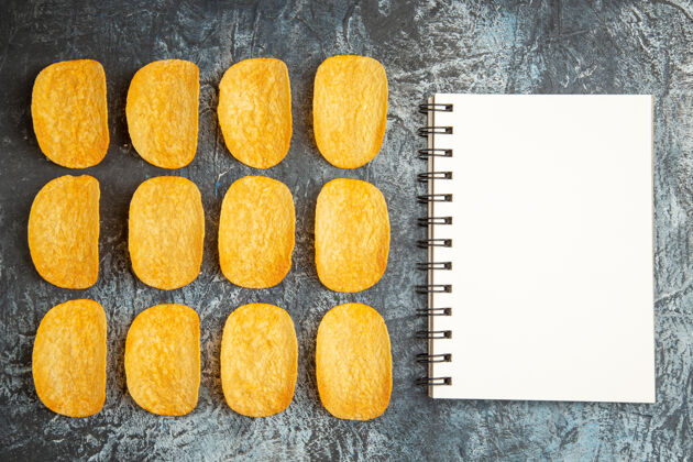 团体俯视图：五个脆皮烤薯片排成一排 笔记本放在灰色的桌子上笔记本有机脆