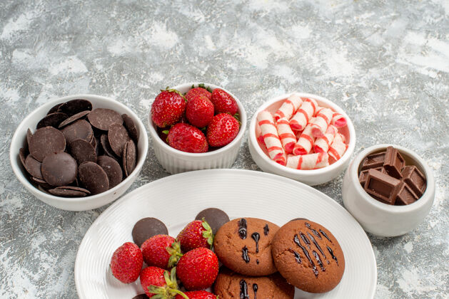 地面下半部分是白色椭圆形盘子上的饼干草莓和圆形巧克力 背景是糖果草莓和巧克力巧克力草莓糖果