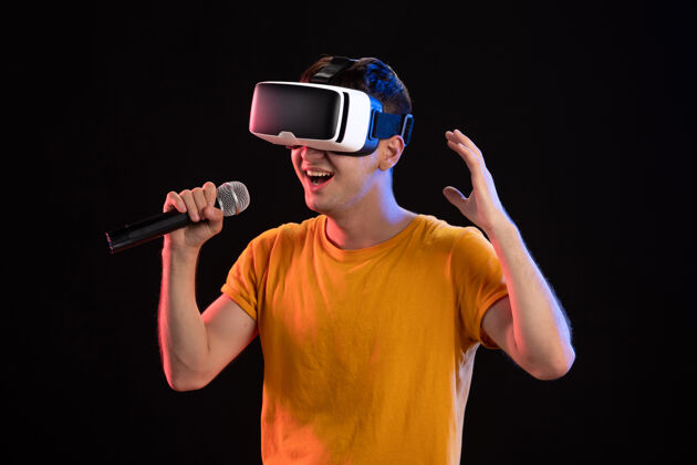 视觉在黑暗的表面上玩虚拟现实和唱歌的年轻人游戏男性虚拟