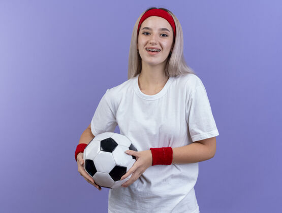 腕带微笑的年轻白人运动女孩戴着背带和头带球运动型头带