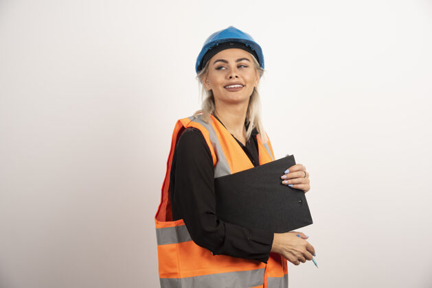 头盔带剪贴板的女工人在白色背景上摆姿势高质量照片职业建筑女人