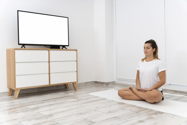 女人运动型女人在家做瑜伽精神智能电视地板