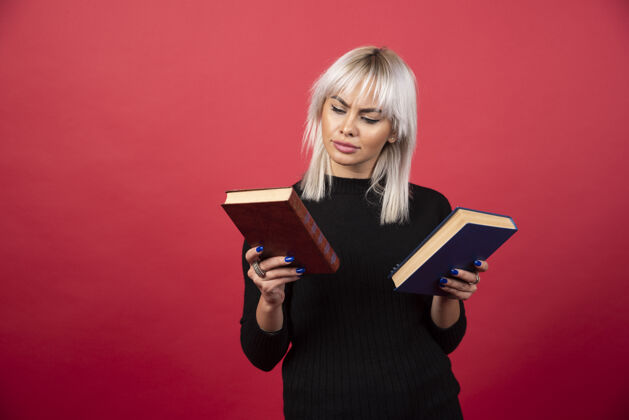 独自年轻的女模特拿着两本红色背景的书高质量的照片手持女人青年