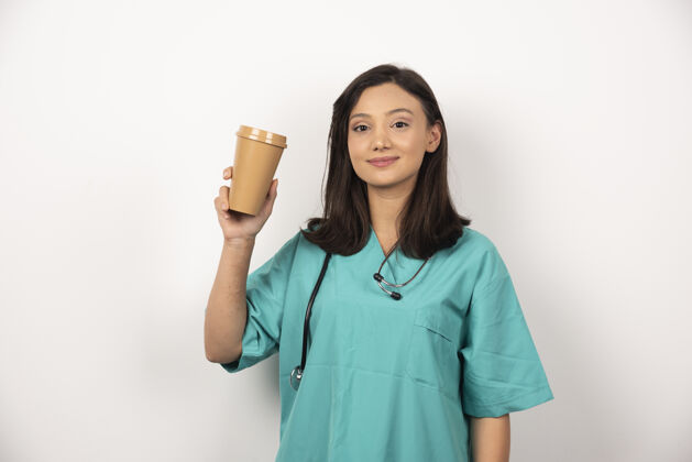 微笑女医生在白色背景上展示一杯咖啡高质量照片阳性制服保健