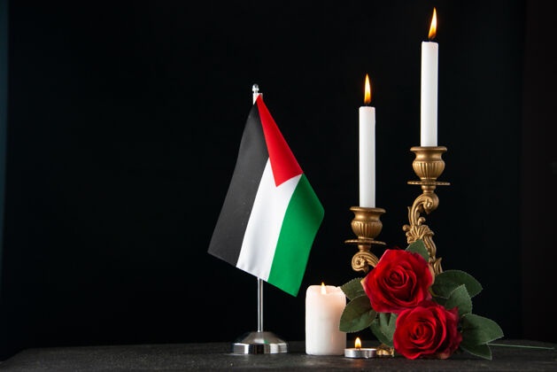 黑暗在黑暗的表面上燃烧着巴勒斯坦国旗的蜡烛的正面图火焰宗教火