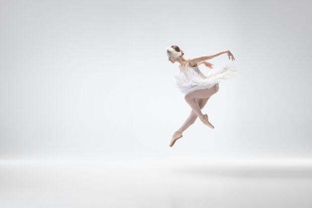 移动以白色工作室为背景的年轻优雅的芭蕾舞演员经典天鹅舞蹈